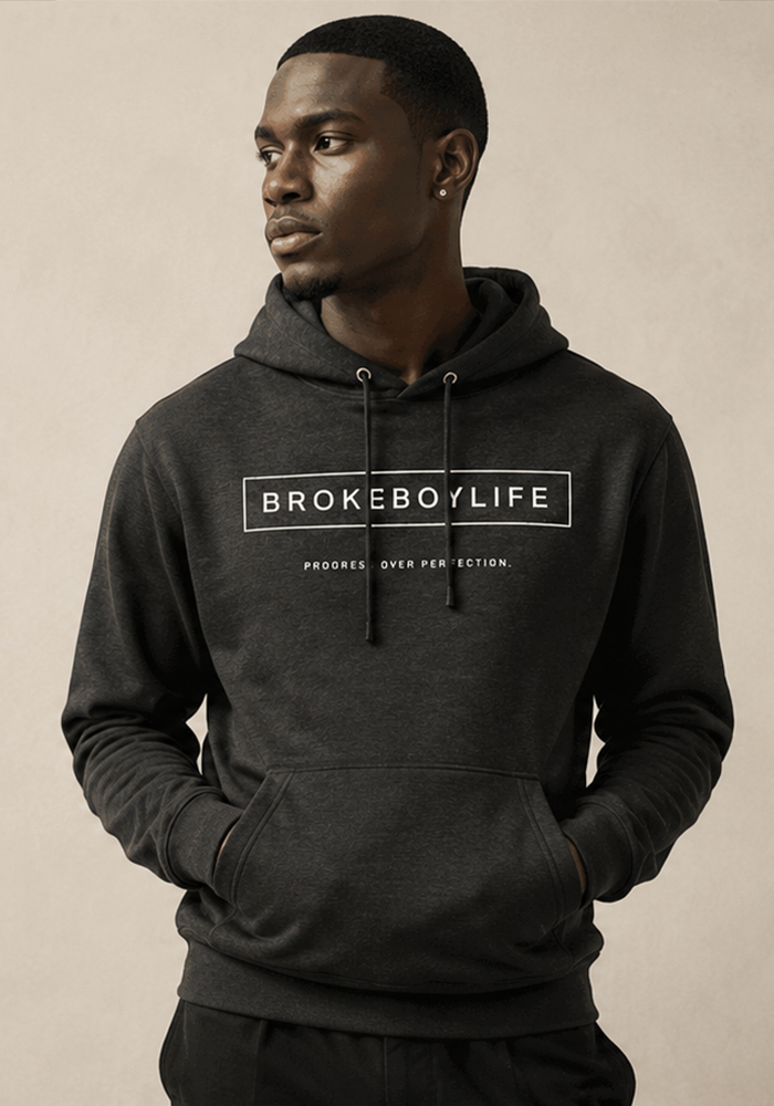 Model wearing the black BROKEBOYLIFE hoodie featuring the signature logo and "Progress Over Perfection" design.