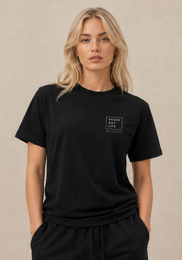 Woman wearing a black BROKEBOYLIFE T-shirt with the minimalist chest logo and "Built on Hustle" detail.